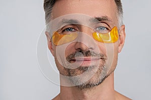 Man applying eye patches. Spa care. Eye patch. Beauty man face with under eye collagen pads. Mature man has fresh