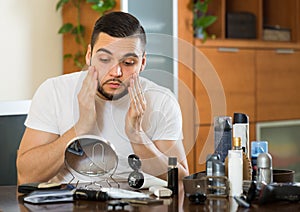 Man applying facial cream at home