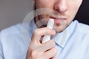 Man applying hygienic lipstick on lips to revive chapped lips and avoid dry, closeup