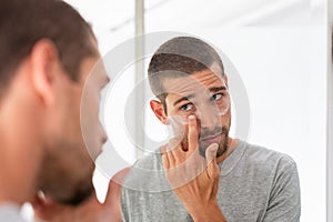 Man applying moisturizer under eyes