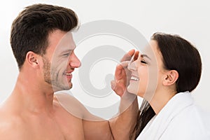 Man applying moisturizer on woman's nose