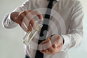 Man applying perfume on wrist indoors, closeu