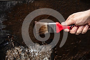 man applying primer with a brush to a damaged bitumen coating photo