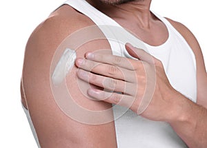 Man applying sun protection cream onto his shoulder against white background, closeup