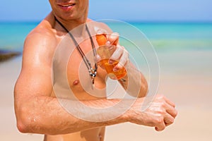 Man applying sunscreen lotion on his body for safe sunbathing