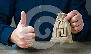 The man approves the deal or loan. Thumbs up and israeli shekel money bag.