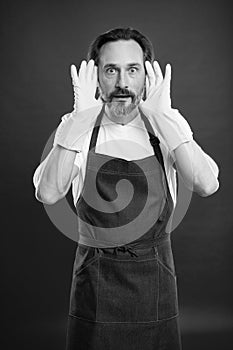 Man in apron with gloves cleaning agent. Cleaning day today. Bearded guy cleaning home. On guard of cleanliness and