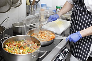 Man in apron and gloves cooking fresh vegetables for healthy food