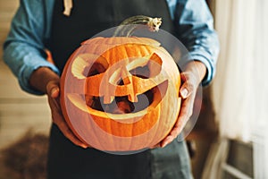 Man in apron with Halloween pumpkin monster spooky jack-o-lantern in hands