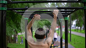 A man of Arab appearance on pull -up bars does exercises. Fitness Sport Street training. Muscles in the public gym.