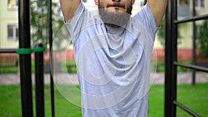 A man of Arab appearance on pull -up bars does exercises. Fitness Sport Street training. Muscles in the public gym.