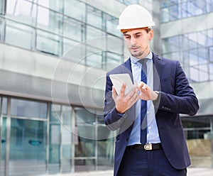 Man architect in helmet working at the tablet
