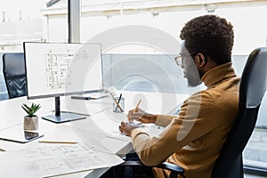 Man architect using engineering computer programs for creating construction project in his workplace