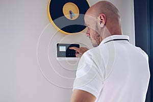 Man arming or disarming a home alarm on the wall.