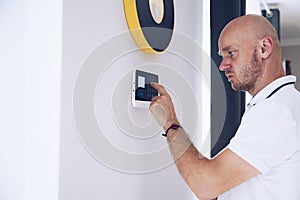 Man arming a home alarm on the wall.