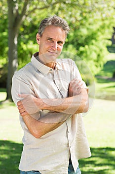Man with arms crossed in park