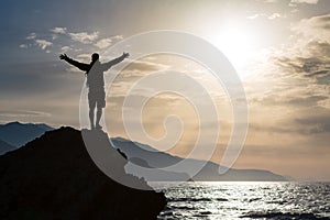 Man with arms outstretched celebrate mountains sunrise