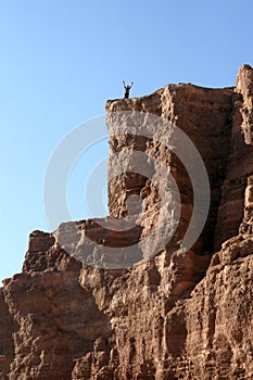 Man with arms raised to the top of the mountain
