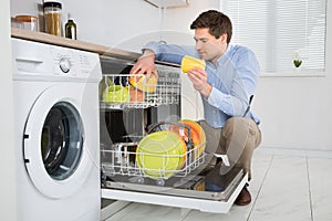 Man Arranging Dishes In Dishwasher photo