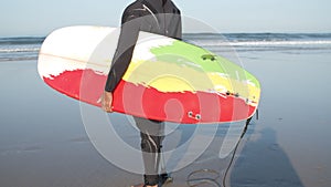 Man with artificial leg standing on beach, holding paddleboard