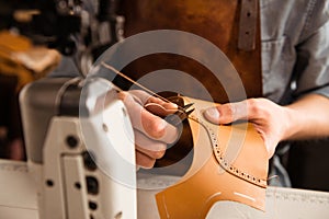 Man artisan sewing leather shoes indoors