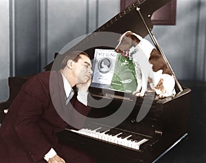 Man asleep at piano with dog photo