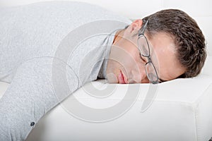 Man asleep on sofa glasses being pushed off face photo