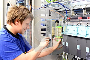 man assembles electronic components on a machine in a factory for mechanical engineering