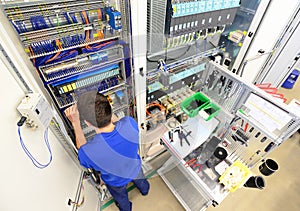 man assembles electronic components on a machine in a factory for mechanical engineering