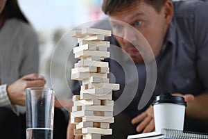 Man assembles a tall tower from wooden rectangular blocks