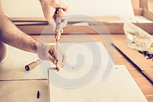 Man assembles wardrobe, twists the screws the slots, furniture assembly