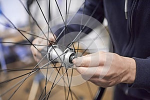 Man assembling a bike wheel axle after the process of cleaning and greasing