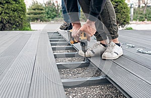 Man assembling composite deck using cordless screwdriver