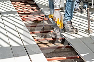 Man assembling composite deck using cordless screwdriver