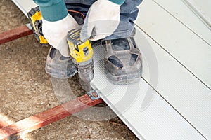 Man assembling composite deck using cordless screwdriver