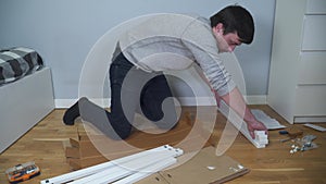 Man assembling flat pack furniture DIY at home on floor. Man bought furniture through online store, assembles table