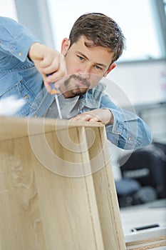man assembling furniture from chipboard boards