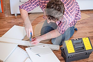 Man assembling furniture at home on the floor