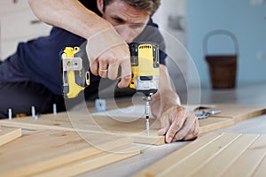 Man assembling furniture at home using a cordless screwdriver