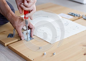 Man assembling furniture at home using screwdriver