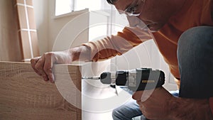 A man assembling furniture in the house