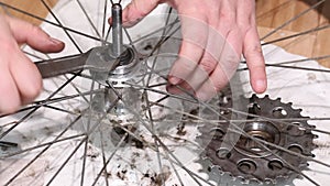 A man is assembling the hub of the rear wheel of a bicycle. Wraps the thrust cone of the ball bearing. Do-it-yourself mountain