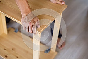 Man assembling wooden furniture at home, close up image