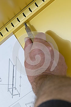 Man assembling a yellow metal cabinet with a screwdriver and instructions.  Self assembly furniture concept