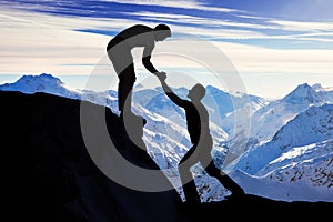 Man Assisting Male Friend In Climbing Rock