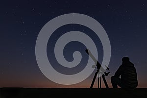 Man with astronomy telescope looking at the stars.