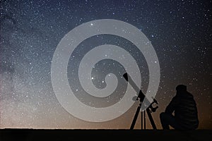 Man with astronomy telescope looking at the stars.