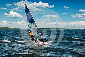 The man athlete rides the windsurf over the waves on lake