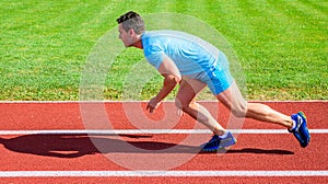 Man athlete runner push off starting position stadium path sunny day. Runner captured in motion just after start of race