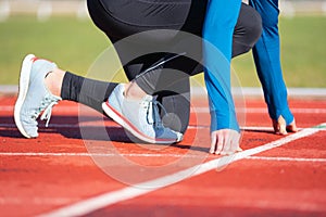 Man athlete on the starting line of a running track at the stadium, close up.